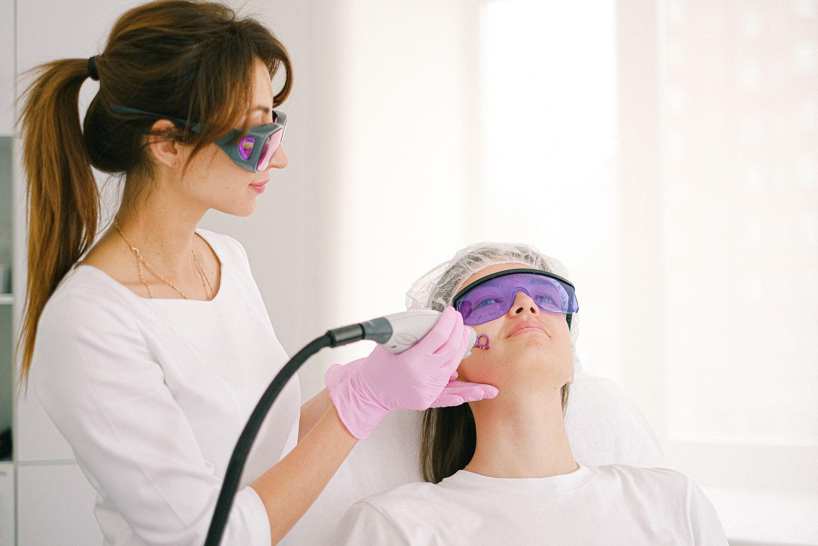 Clinician performing a laser skin treatment with protective eyewear in a clinic setting