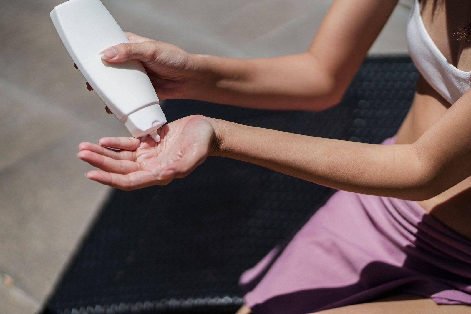 Person dispensing sunscreen into their hand, representing daily photoprotection